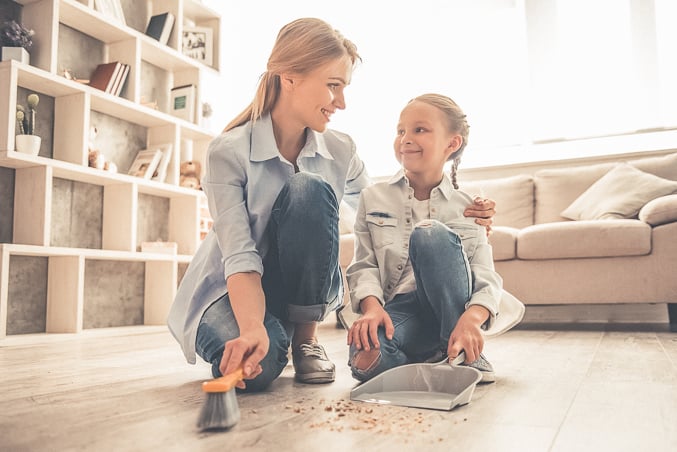 mom teaching child how to be productive by showing her how to sweep floor
