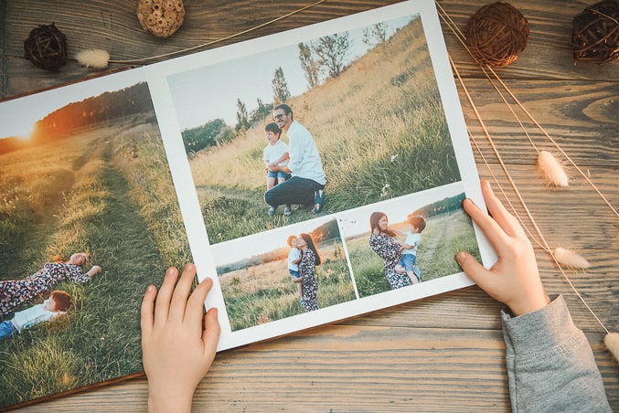 childs hands holding an open family photo album on table